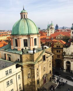 Church and buildings in city against sky