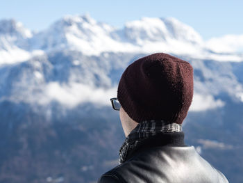 Rear view of man with snow on mountain against sky