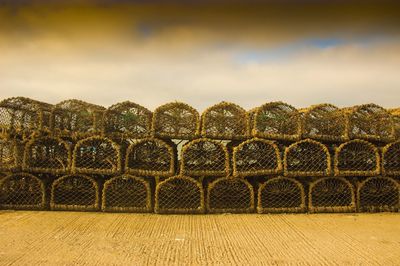 Lobster traps for sale on footpath against cloudy sky