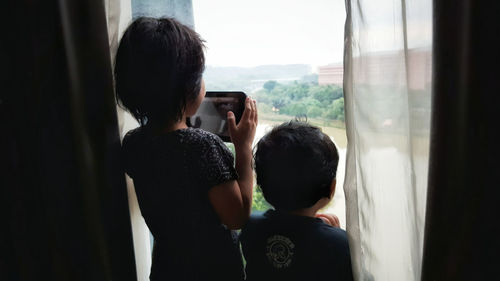 Rear view of people photographing through window