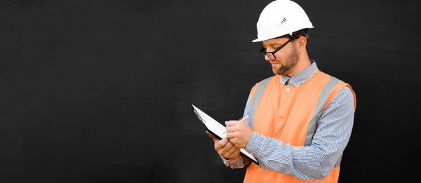 Man in white hard hats. confident build worker, black background. copy space. construction industry