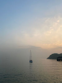 Sailboat sailing on sea against sky during sunset