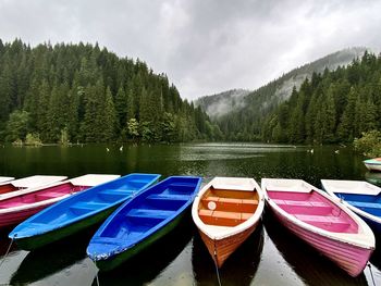 Boats moored by lake against sky