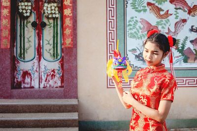 Teenager holding hand fan standing at temple