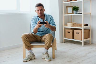 Portrait of young man using mobile phone while sitting at home