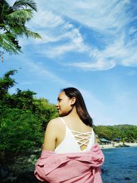 Beautiful young woman looking away against sky