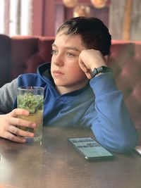 Portrait of boy drinking  cocktail from glass on table