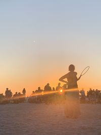 Woman on beach against sky during sunset