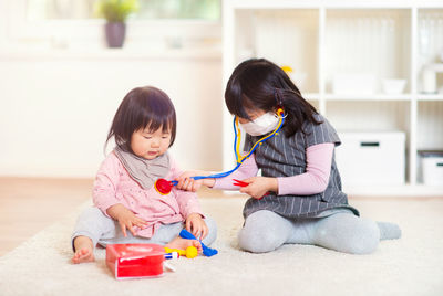 Cute girl playing with toy while sitting on floor