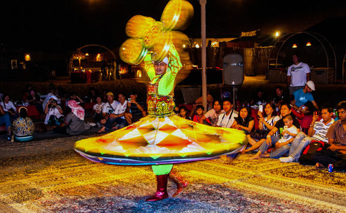 People in illuminated traditional clothing at night