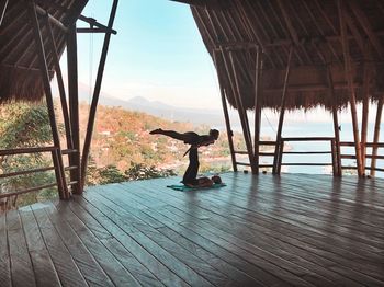 Full length of women doing yoga in thatched roof