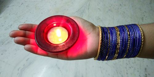 Close-up of hand holding illuminated electric lamp