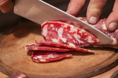 Cropped image of hand slicing cold cuts