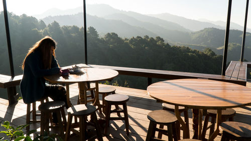 Woman sitting in cafe against mountains