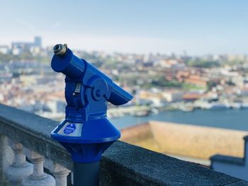 Close-up of coin-operated binoculars against buildings in city