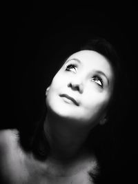 Close-up portrait of a young woman over black background