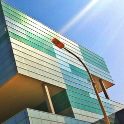 Low angle view of glass building against blue sky