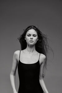 Portrait of young woman standing against wall