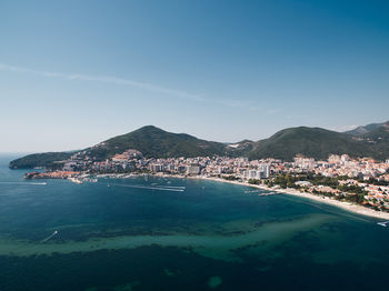 High angle view of townscape by sea against clear blue sky