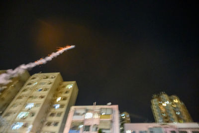 Low angle view of illuminated buildings against sky at night