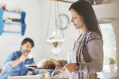 Woman holding food while standing in kitchen