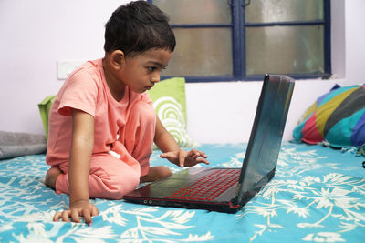 Cute girl using laptop on bed at home