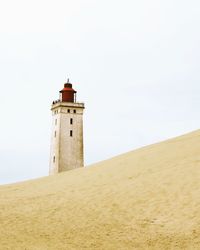 Lighthouse by sea against sky