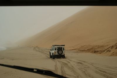 Offroad vehicle on sand seen through windshield