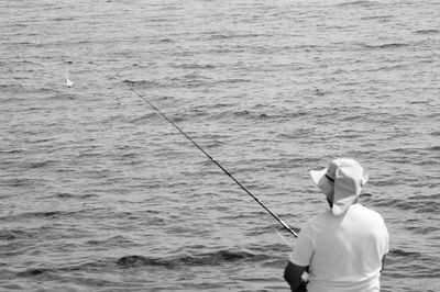 Rear view of man fishing in sea