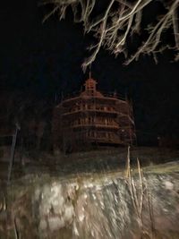 Digital composite image of illuminated building against sky at night