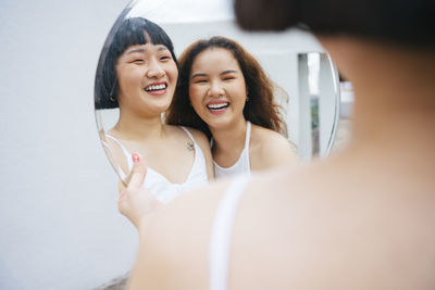 Reflection of lesbian sisters holding mirror outdoors