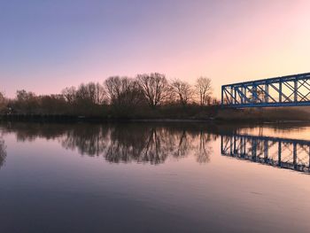 Bridge over river against sky at sunset