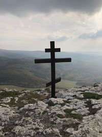 Cross on land against sky