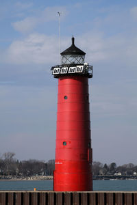 Lighthouse by building against sky