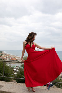 Woman in red dress standing against sky