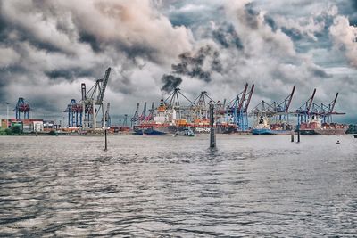 Cranes at commercial dock against sky