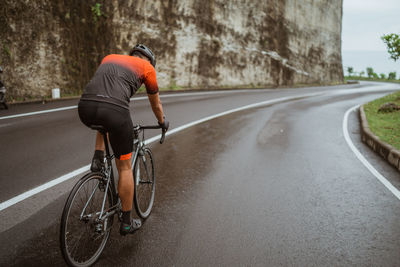 Rear view of man riding bicycle on road