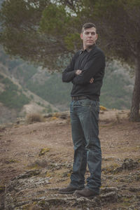 Portrait of a young man standing on tree trunk