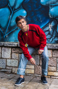 Portrait of young man standing against wall