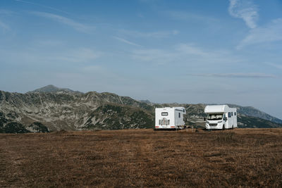 Camper van on field against mountains and sky