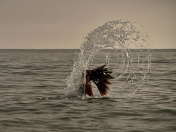 Man swimming in sea against clear sky