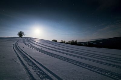 Snow covered landscape against sky at night