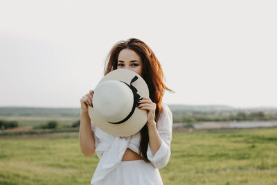 Portrait of woman with sun hat standing on land against clear sky during sunset