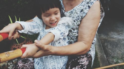 Midsection of mother with daughter holding equipment outdoors