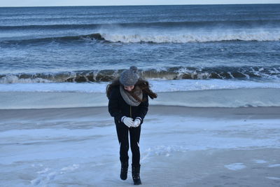 Full length of woman holding snow at beach