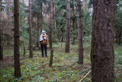 Woman standing against trees in forest