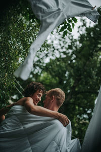 Rear view of couple kissing against trees