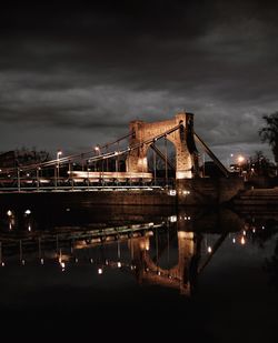 Illuminated bridge over river against sky at night