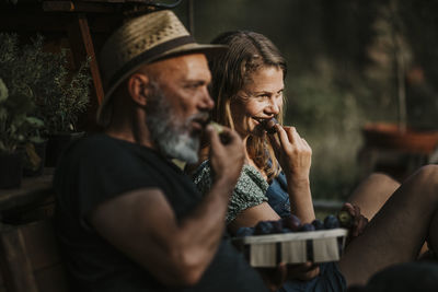 Midsection of man holding woman sitting outdoors