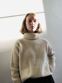 Portrait of beautiful young woman standing against wall at home